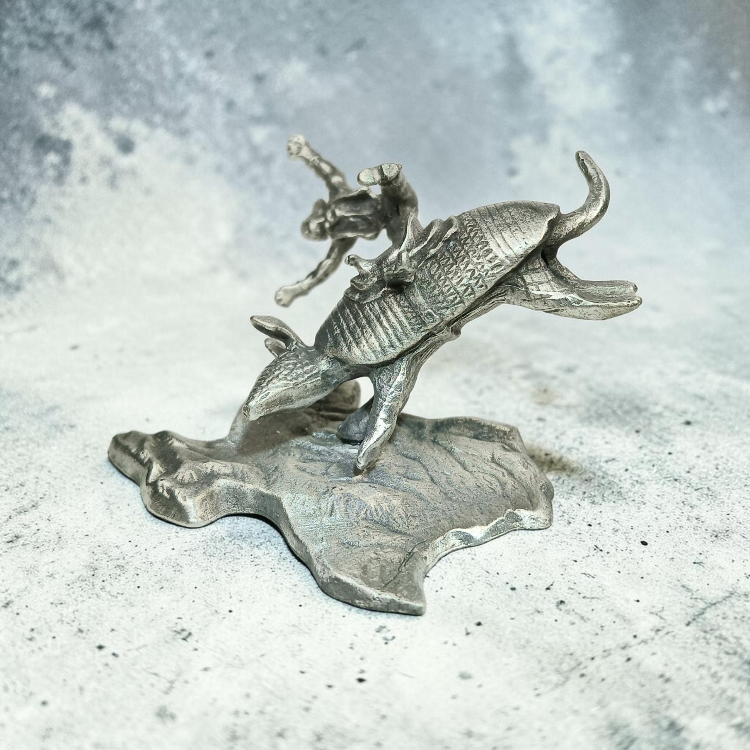 Side view of an armadillo sculpture with an airborne cowboy on a Texas-shaped base.