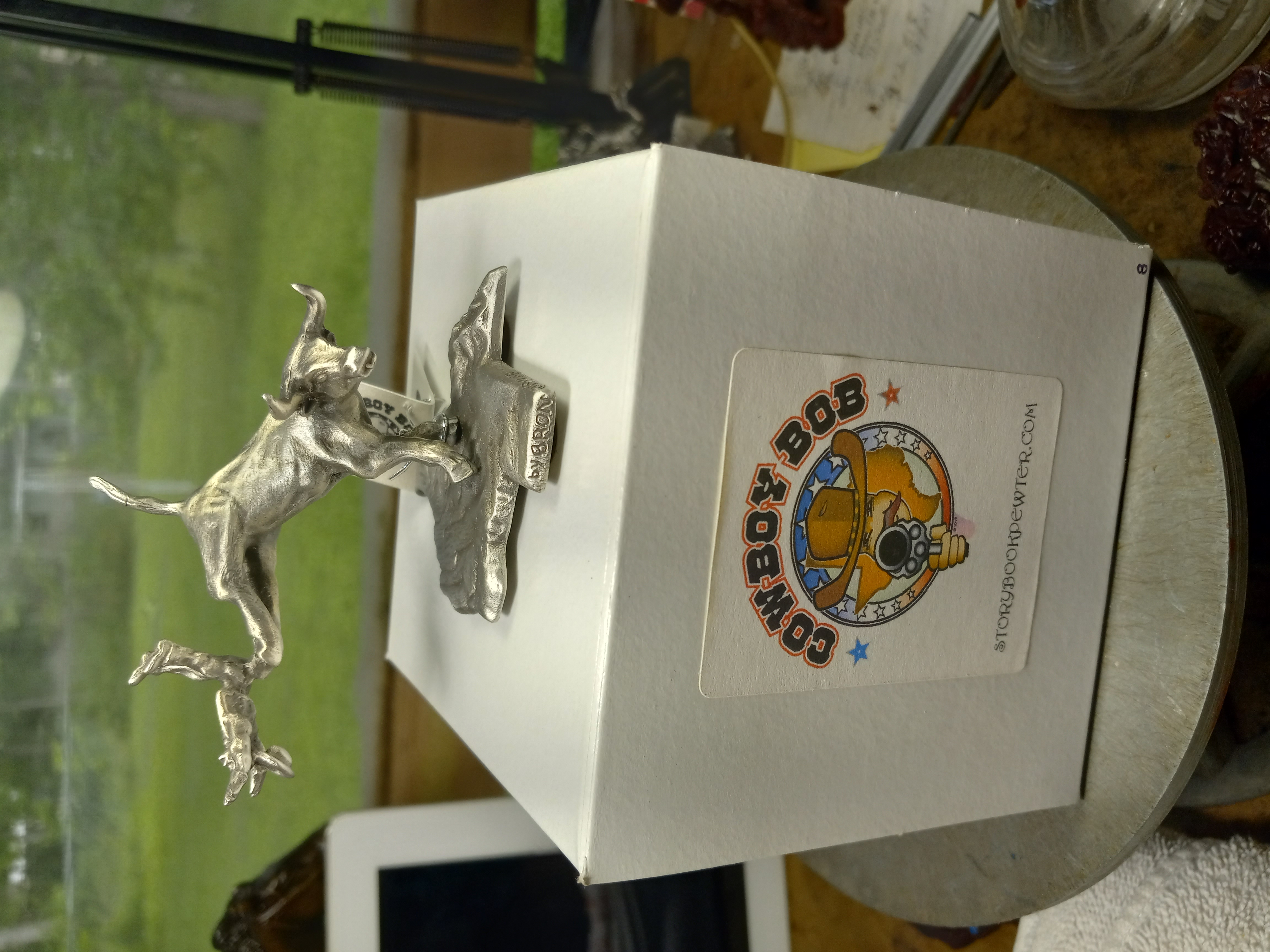 Side view of a pewter bucking bull sculpture on a Cowboy Bob display box.
