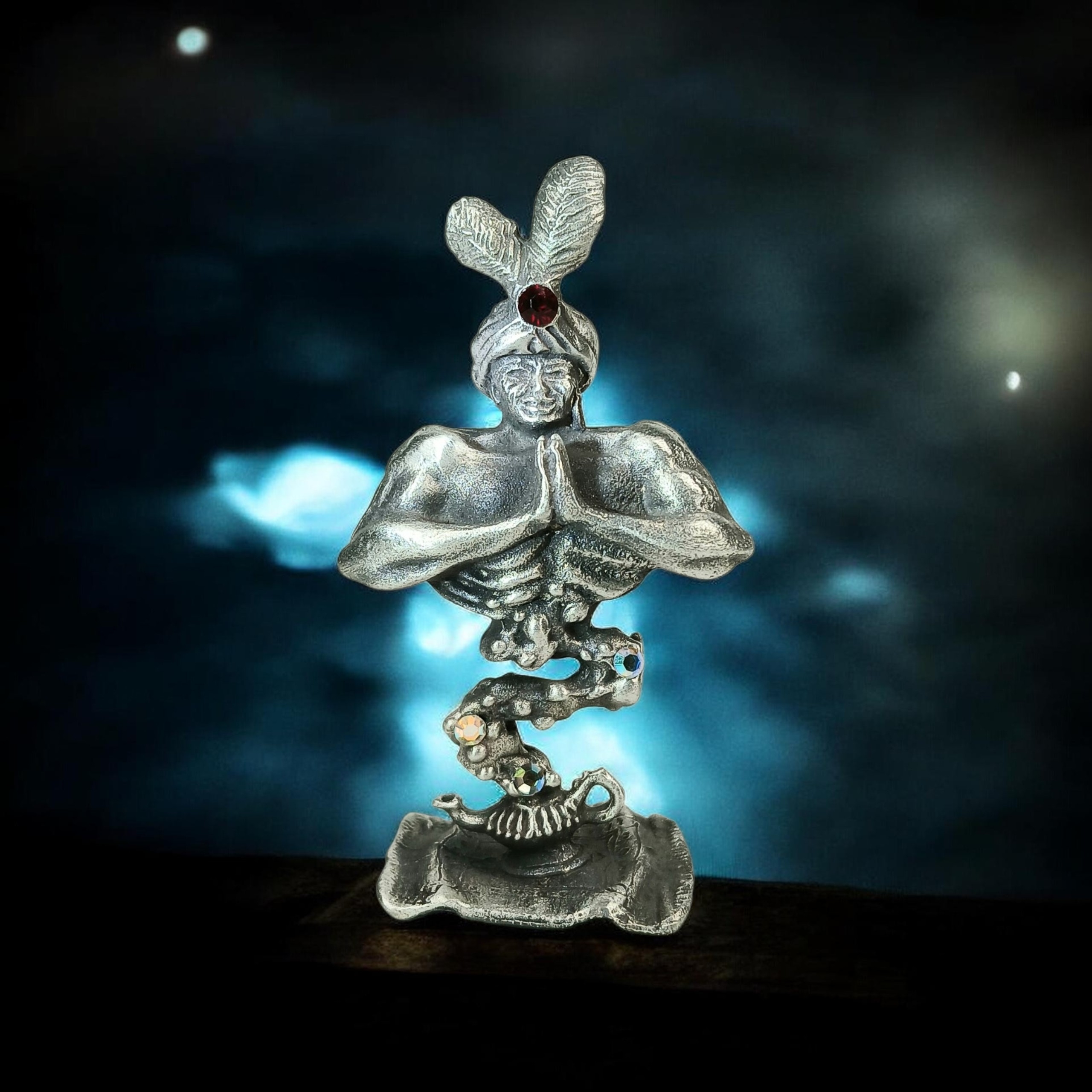 Pewter genie wearing a feathered turban, with joined hands and a curling base.